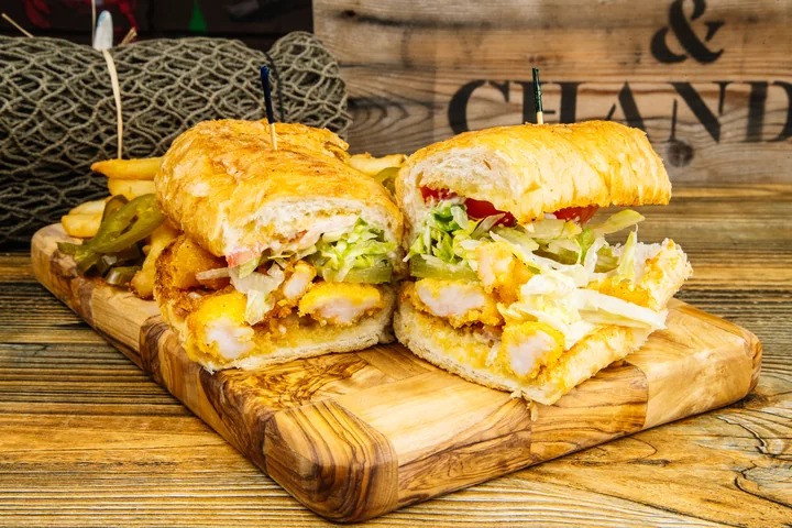 A toasted seafood po’ boy sandwich served with fries